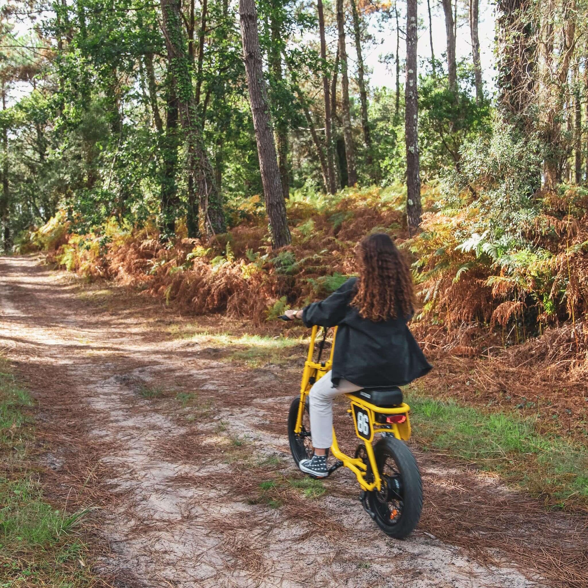 vrouwelijk-model-rijdend-in-het-bos-op-de-gele-voltaway-passenger-fatbike